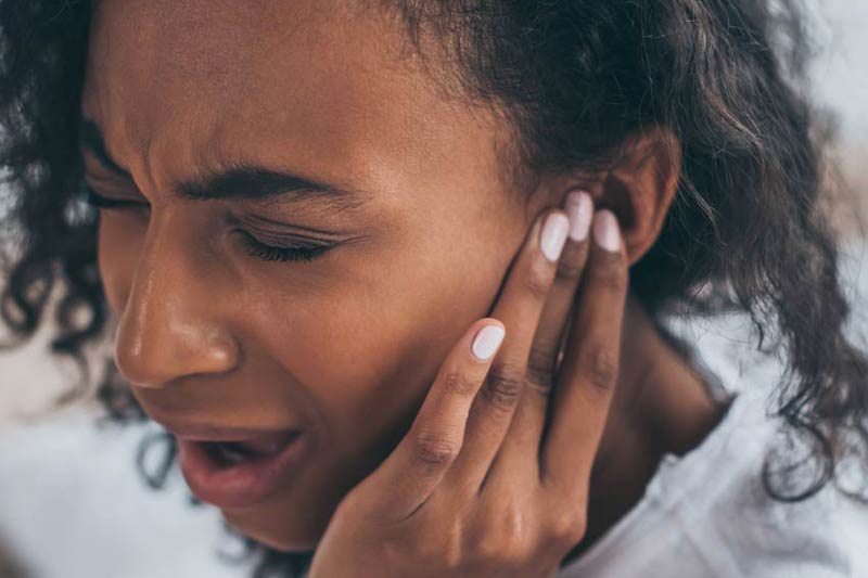 Woman holding ear in pain