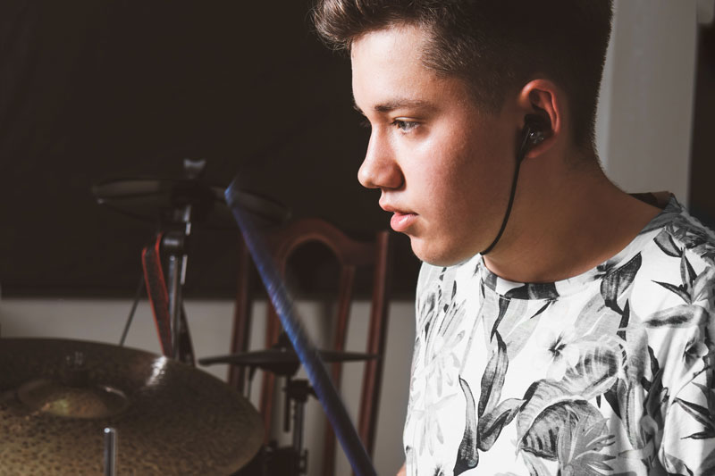 Teenage male drummer performing in a studio