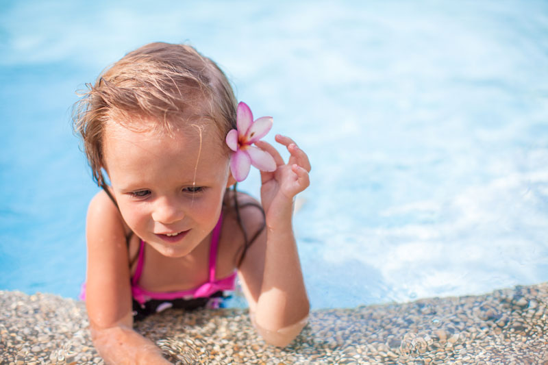Little girl with flower behind her ear in pool