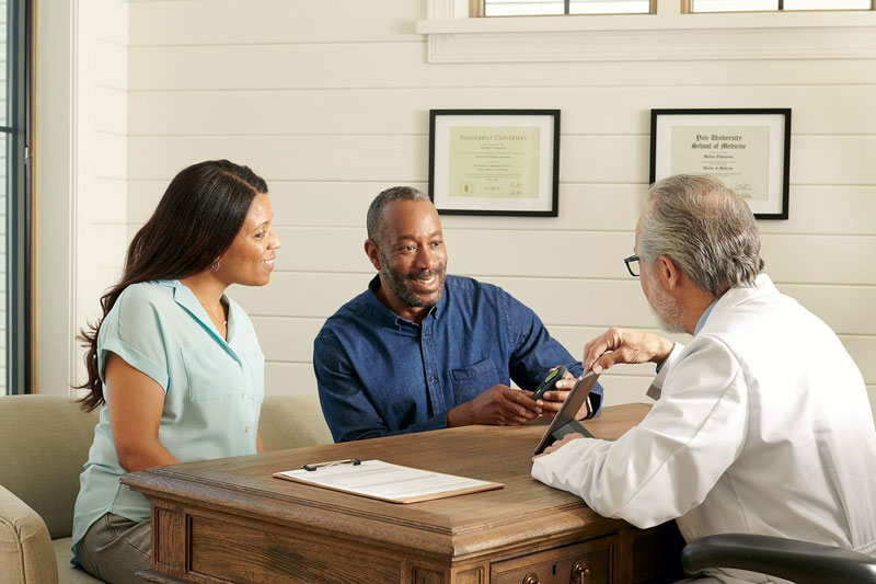 Man and woman sitting at desk learning about procedure with physician