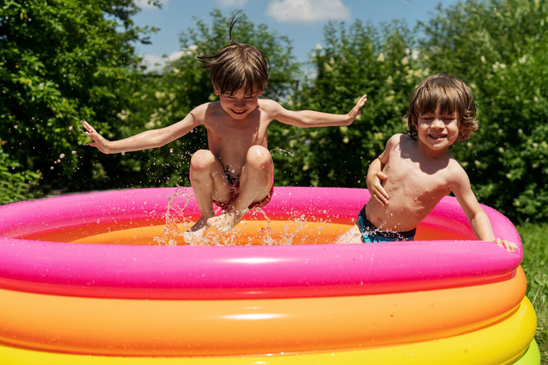 Two young boys play in an inflatable pool