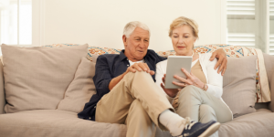 Older couple sitting on couch and reviewing something such as their ENT health on their tablet
