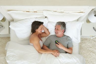 Man and woman laying in bed holding remote for Inspire